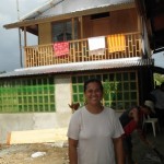Dahlia Baltazar, Wife of Pastor Mike, with parsonage, built with donated materials.